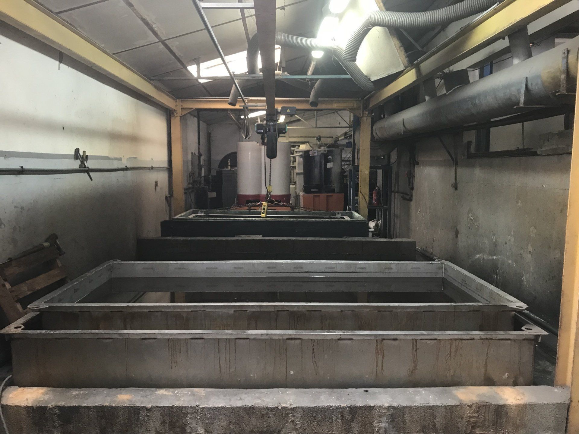 Des pièces métalliques jaunes sont suspendues à un support jaune dans un environnement d'usine.