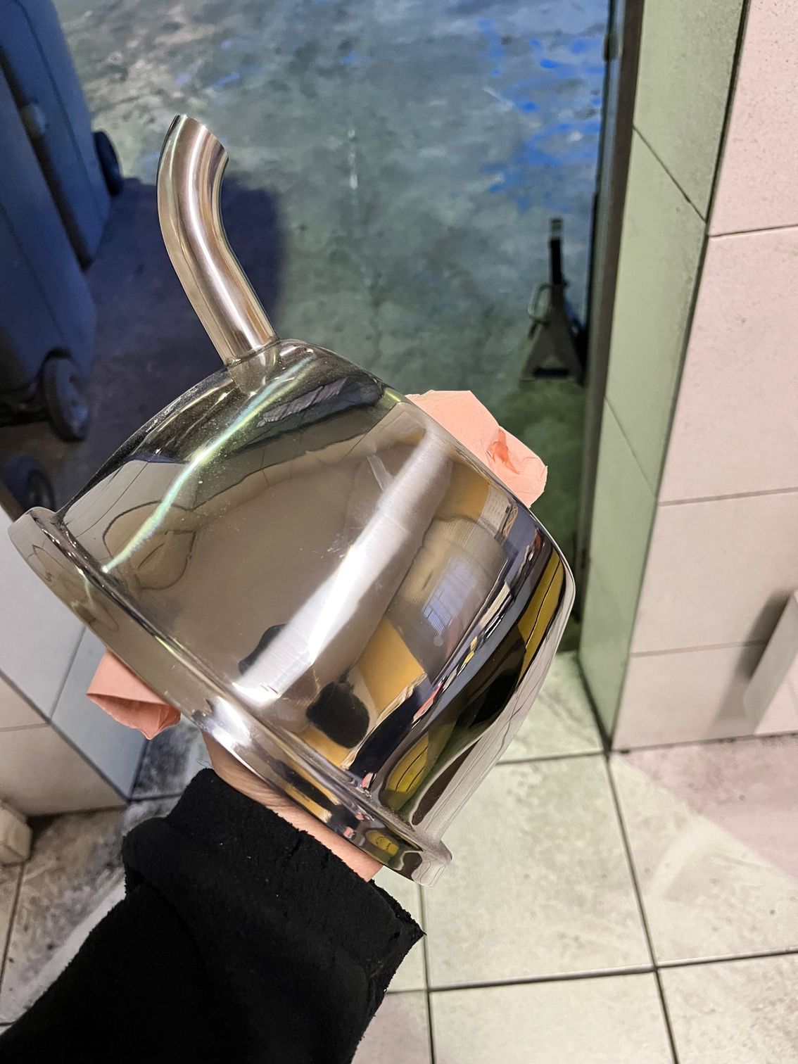 Une personne tenant un pichet en métal argenté brillant.