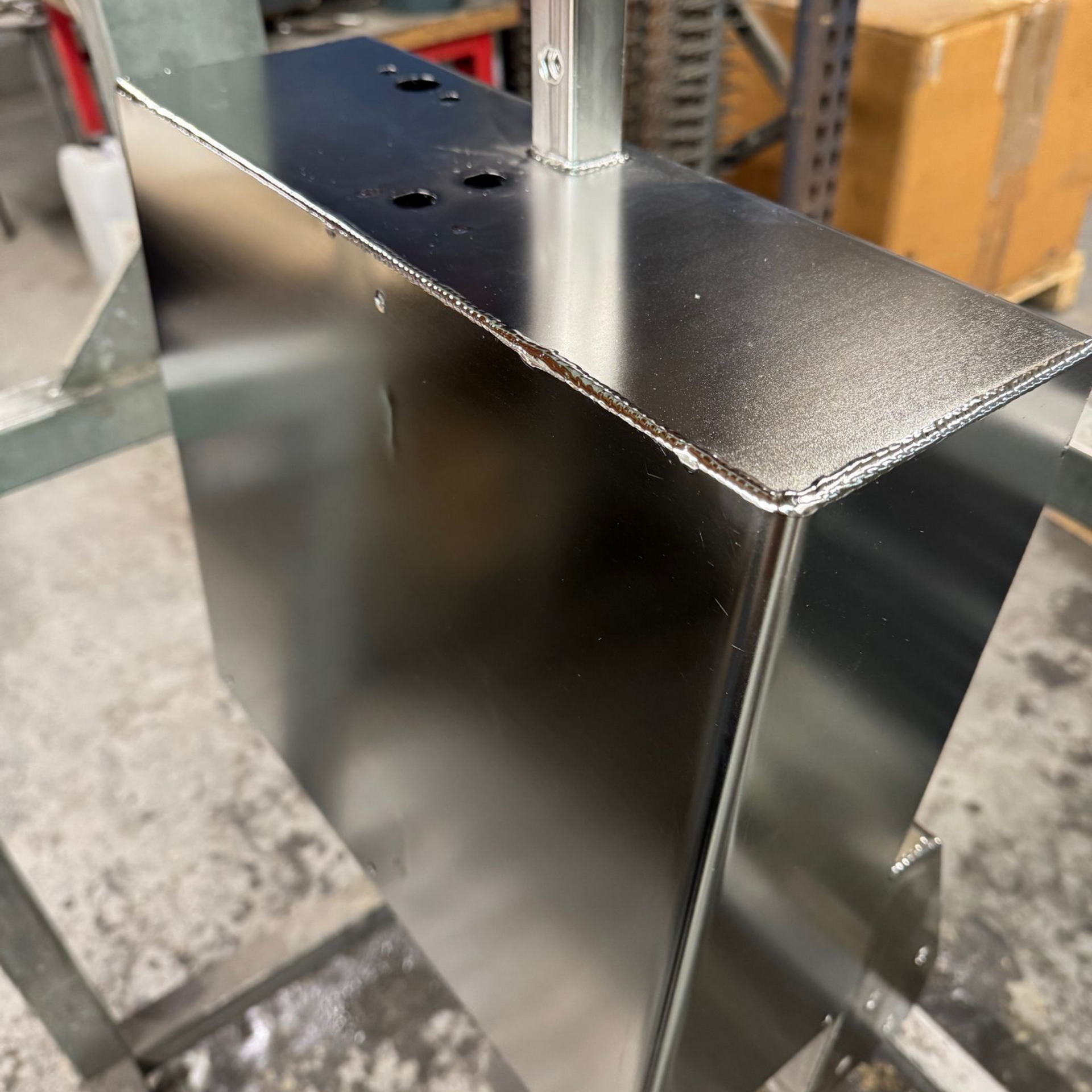 Divers objets métalliques brillants, notamment des accessoires de plomberie, des ustensiles et des objets décoratifs, disposés sur une surface grise.