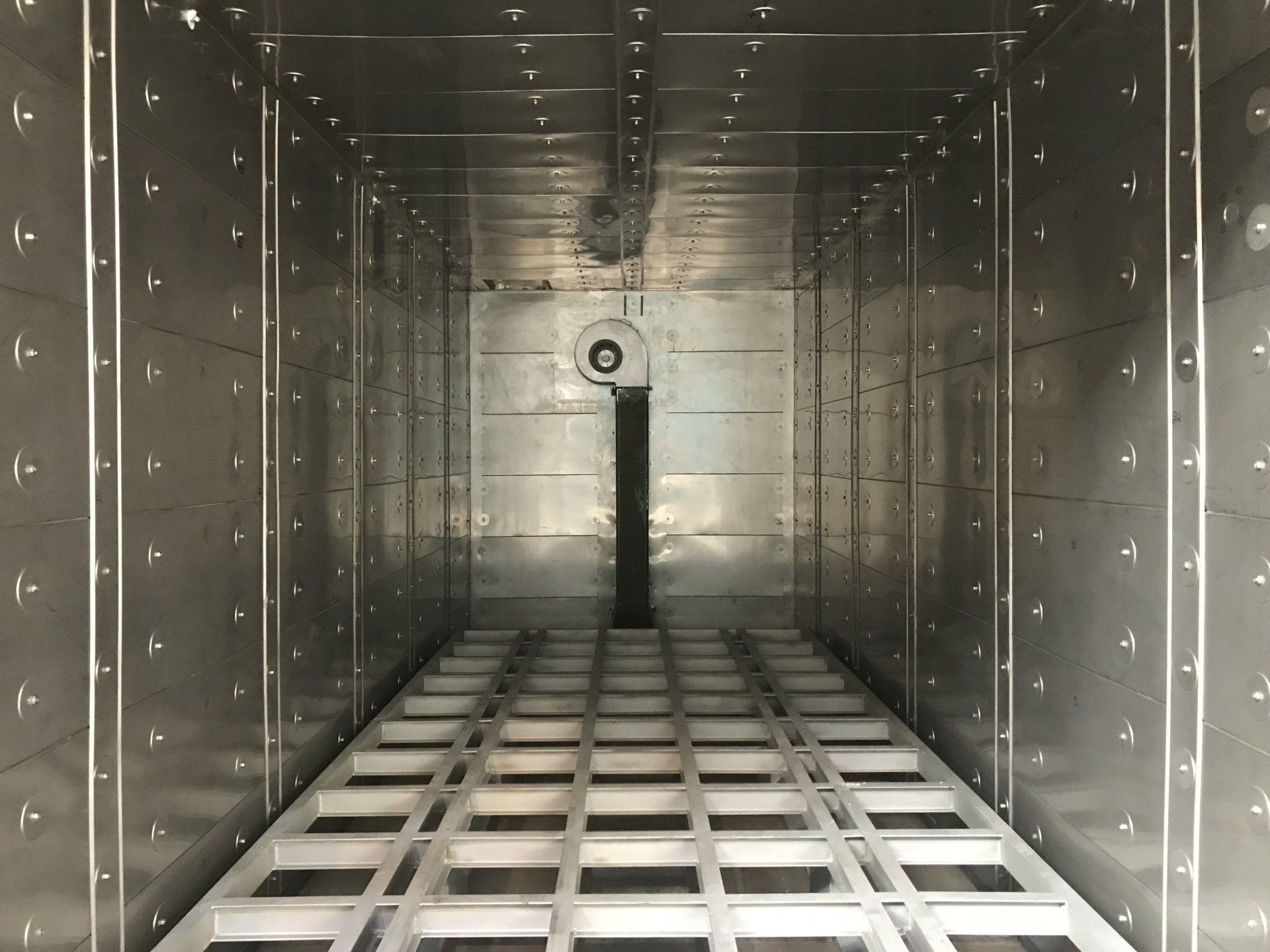 Vue intérieure d'un grand four industriel en acier inoxydable avec ventilateur et grille.