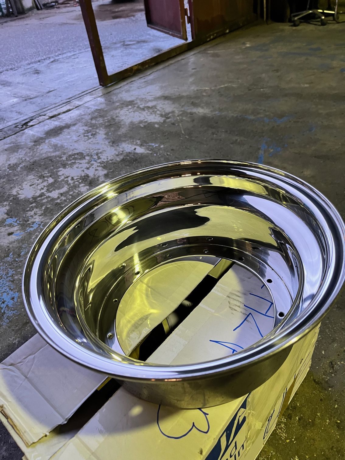 Jante chromée brillante posée sur une boîte en carton, en extérieur.