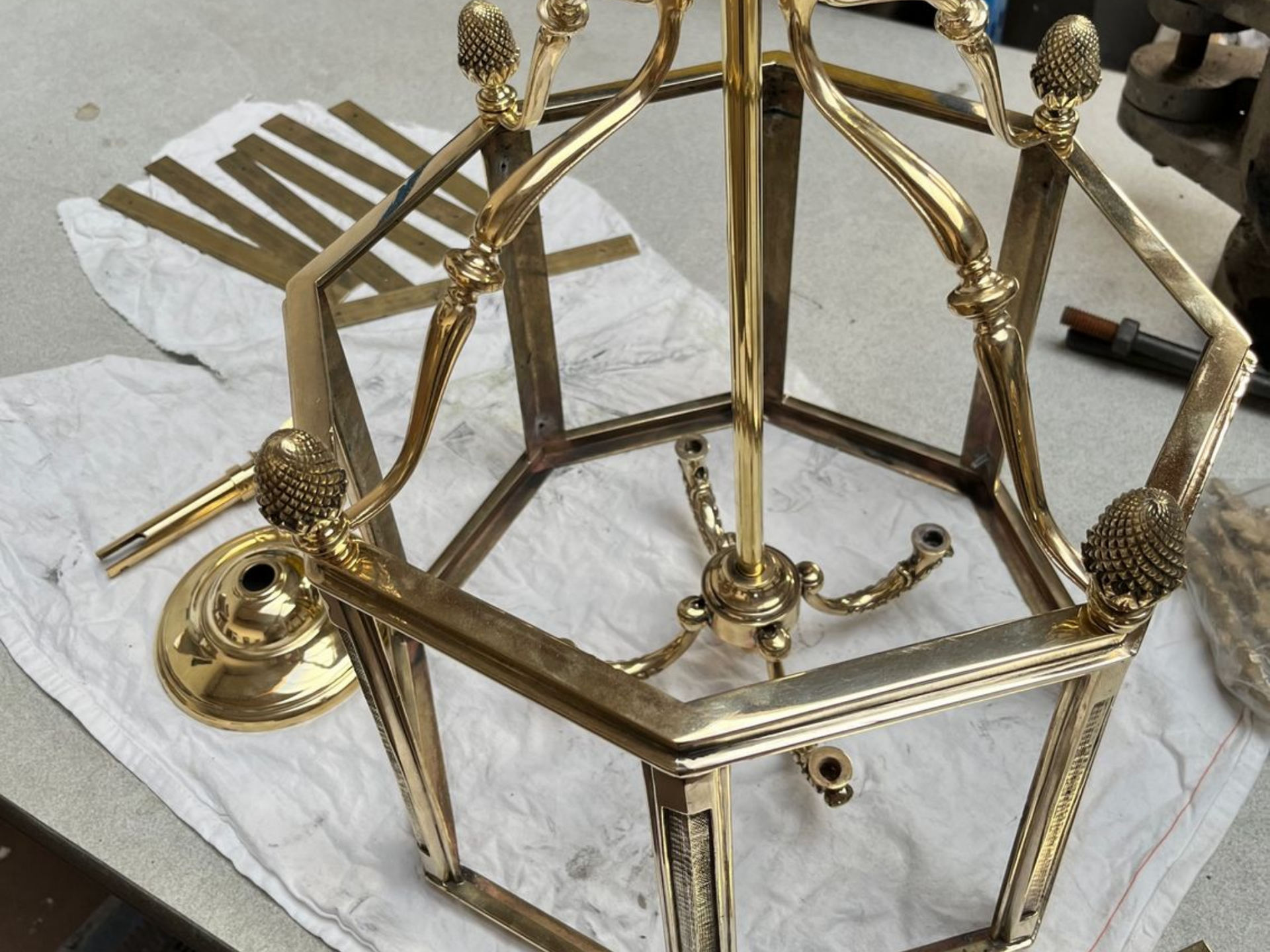 Cadre de lustre hexagonal doré avec embouts décoratifs et tige centrale.