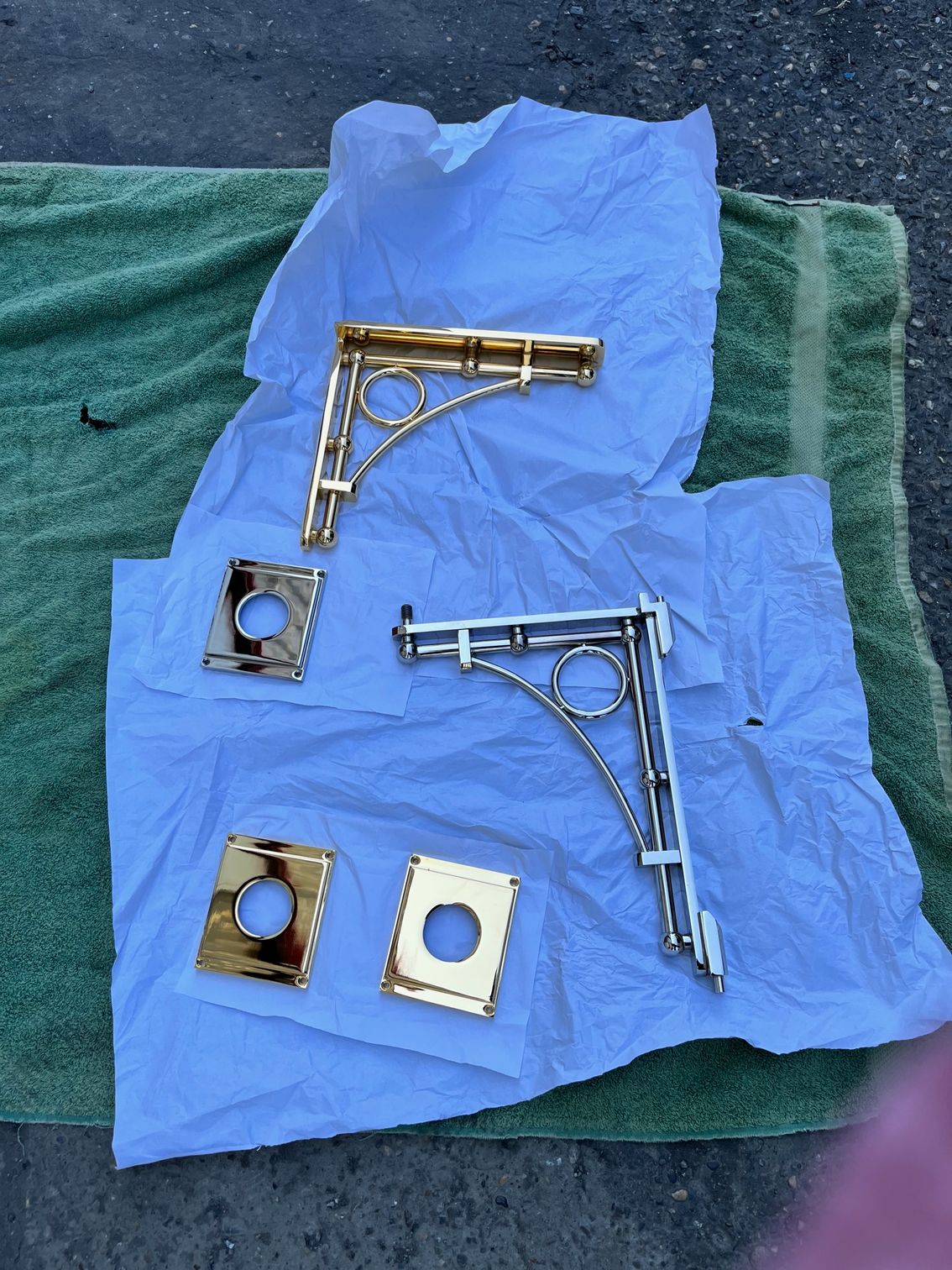 Deux supports d'étagère en laiton et des assiettes carrées sur une serviette en papier blanche, un ensemble semble doré, l'autre argenté.