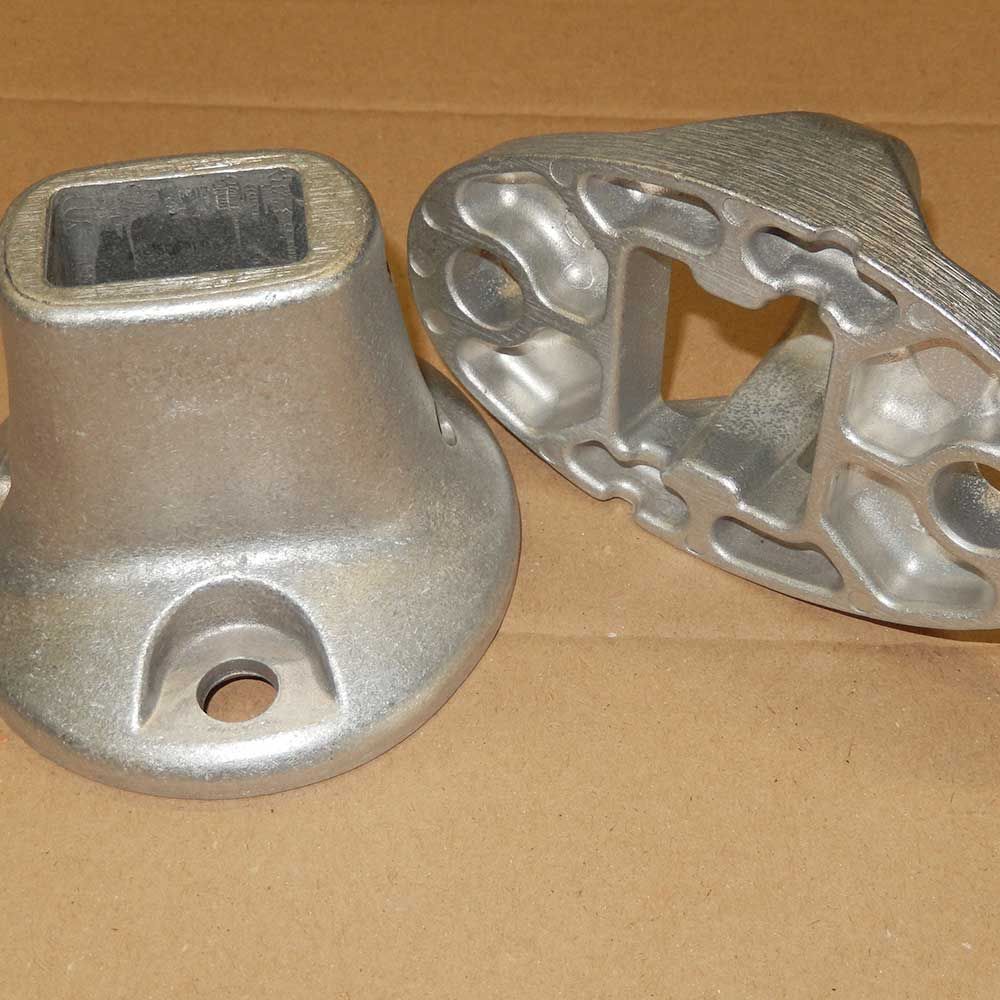 Deux pièces en métal moulé avec des ouvertures carrées et rectangulaires et des trous de fixation.