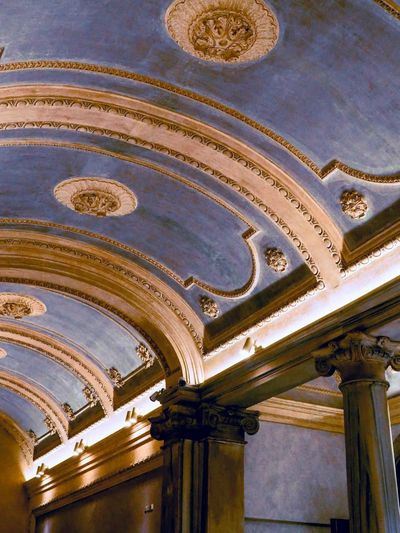 Soffitto decorato con archi blu, finiture dorate e colonne in un interno elegante