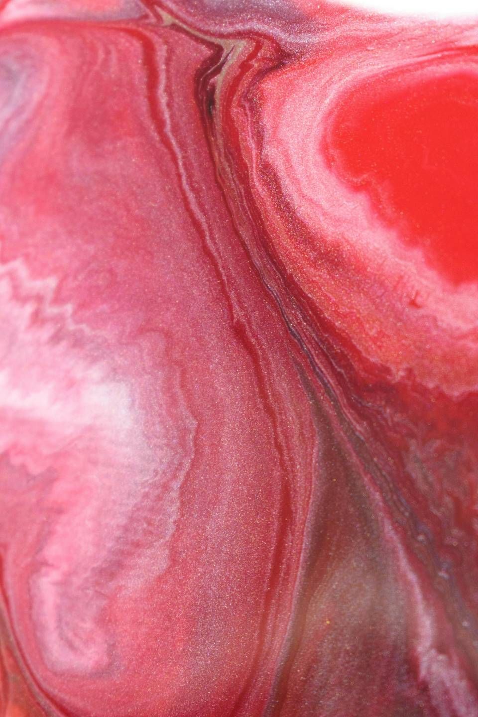Texture astratta marmorizzata rosa e rossa con striature bianche fluide.
