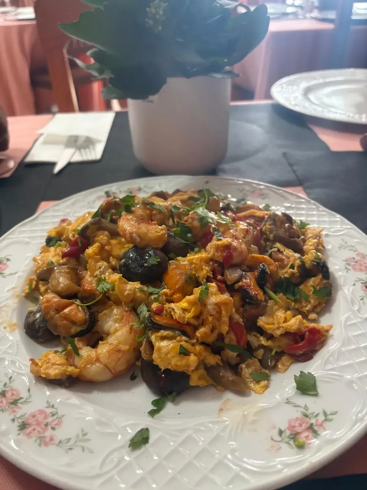 Arroz frito cubierto con camarones en un plato blanco, con guarnición de cebolla verde.