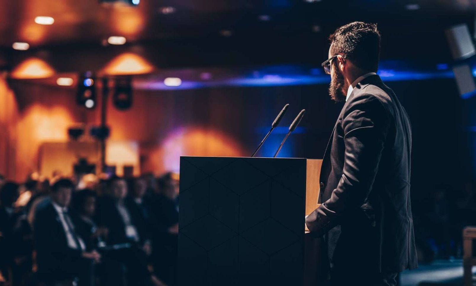 Redner am Pult vor einem aufmerksamen Publikum