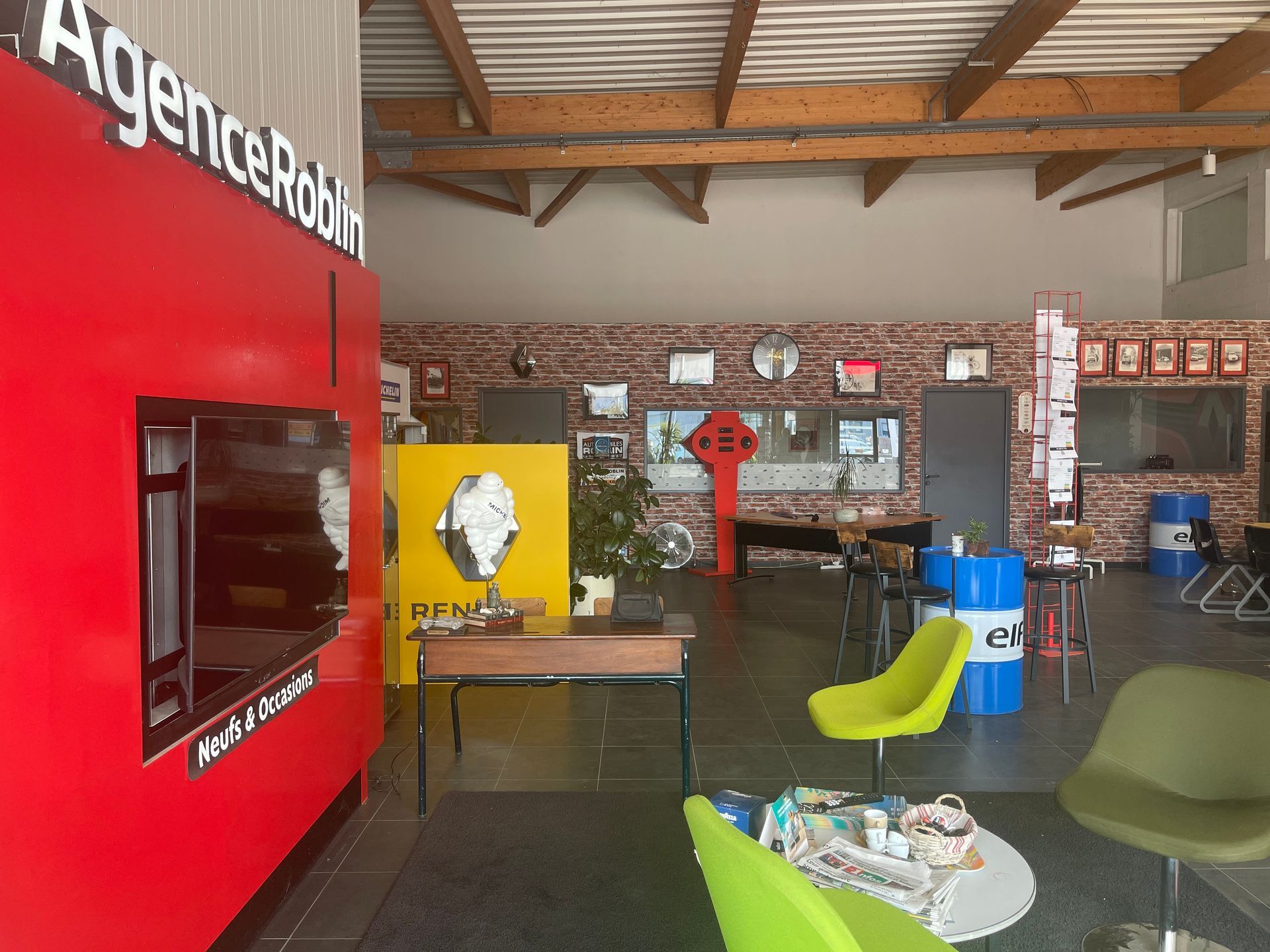 Intérieur d'un bureau aux touches de rouge, de jaune et de vert. On y voit un écran, des sièges et un bureau.