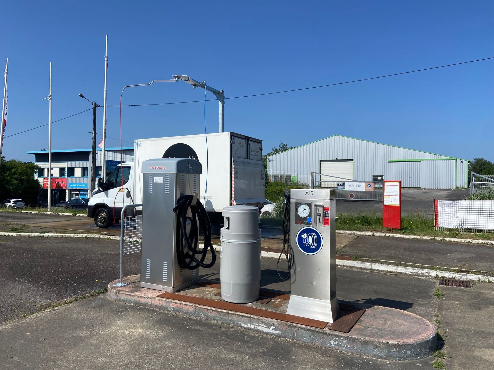 Une personne lave une voiture noire avec de l'eau savonneuse à l'aide d'un nettoyeur haute pression dans un lave-auto.