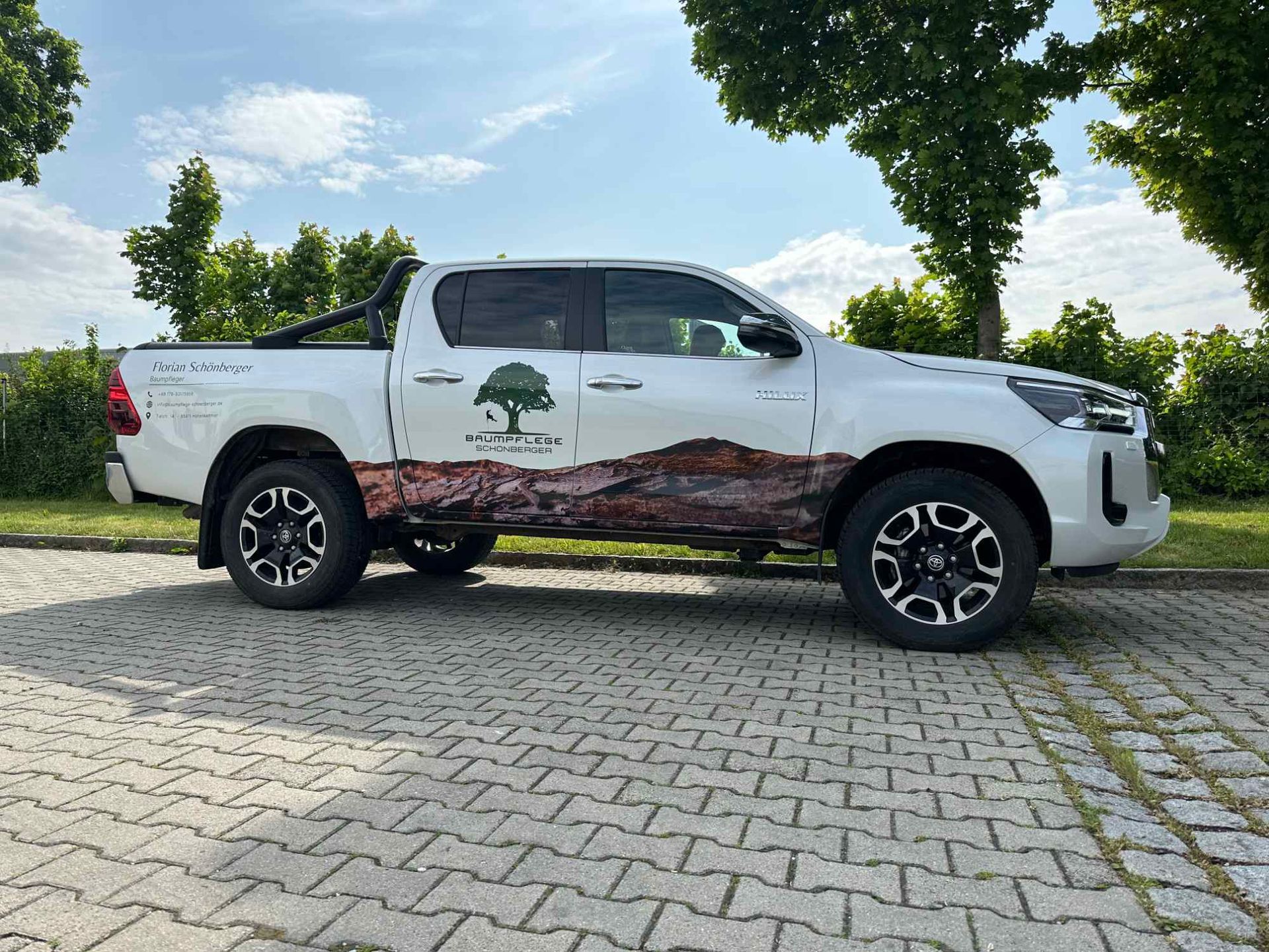 Ein Pickup ist foliert mit einer Steinlandschaft und einem Logo in Form eines Baumes