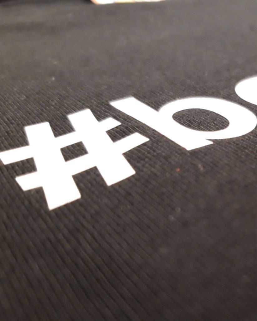 Schwarzes T-Shirt in Nahaufnahme, auf dem ein Hashtag aufgedruckt ist