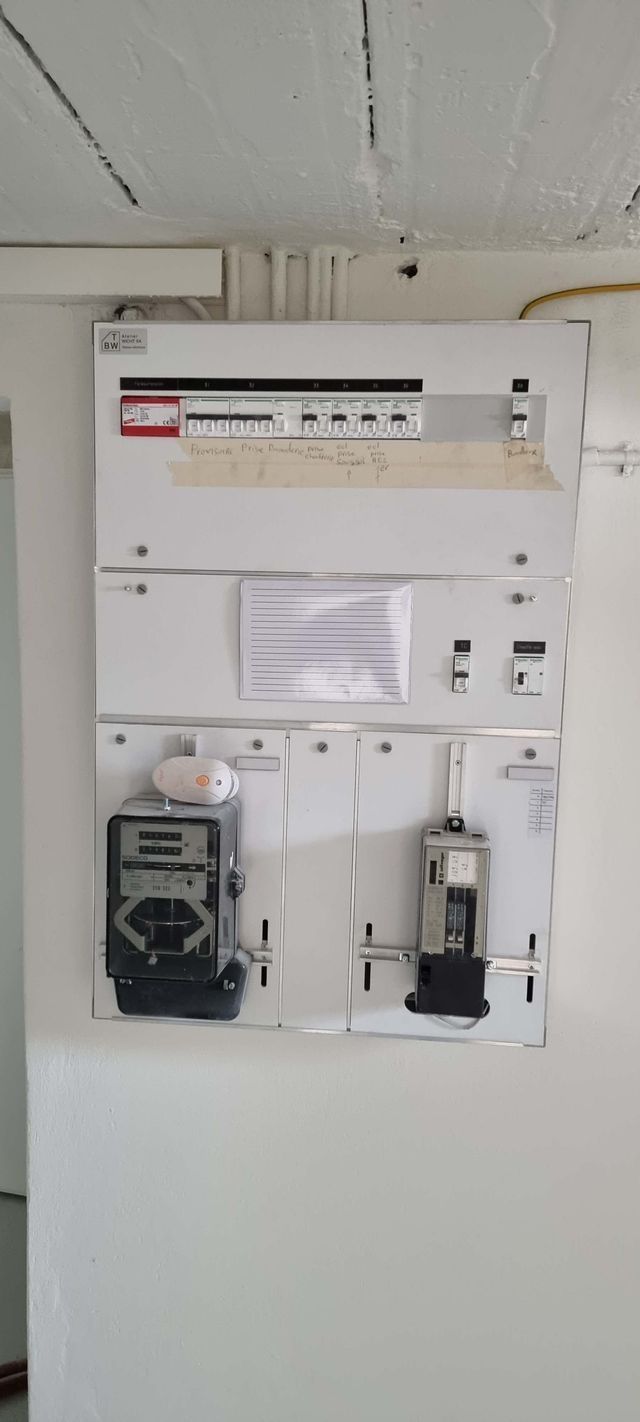 Un mur blanc avec un coffret électrique et un compteur dessus.