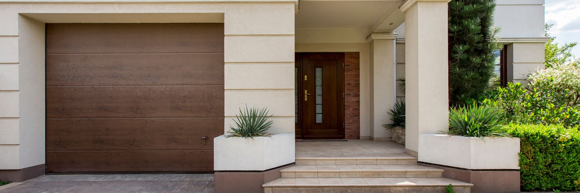 Extérieur d'une maison moderne avec une porte de garage marron et une porte d'entrée avec marches.