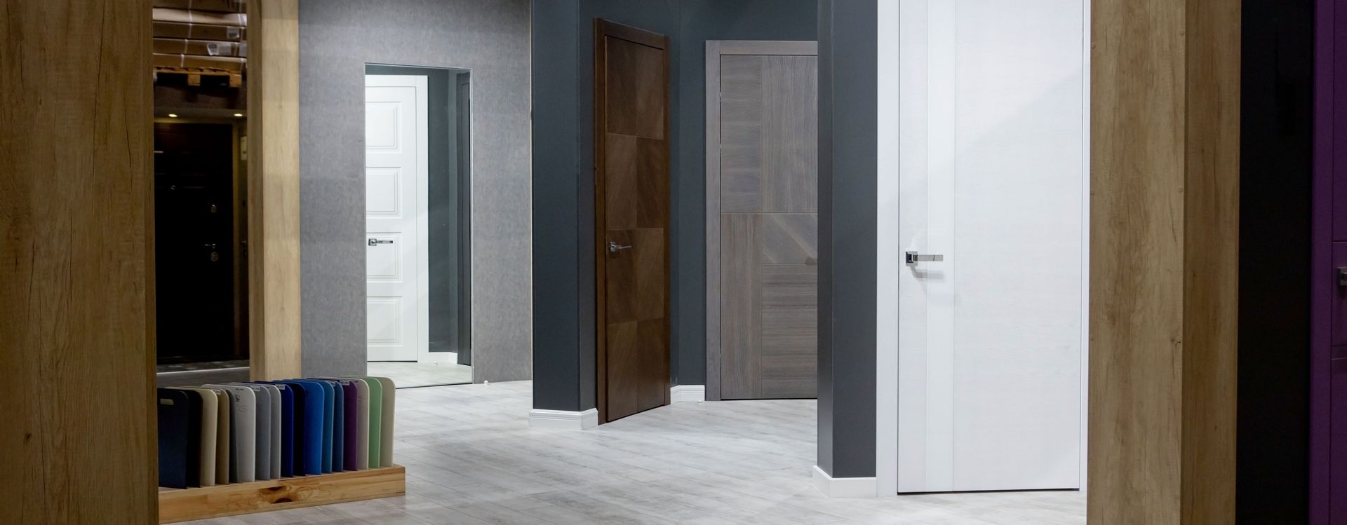 Plusieurs portes fermées exposées dans une salle d'exposition, de couleurs et de designs variés.