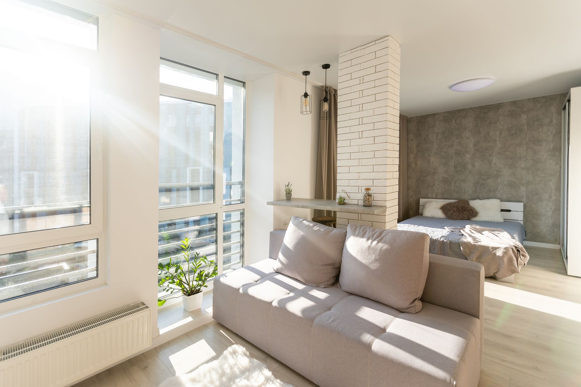 Intérieur d'appartement moderne avec un canapé, un lit et une grande fenêtre.