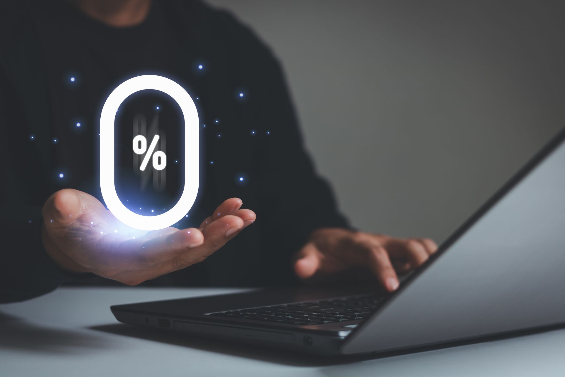 Personne utilisant un ordinateur portable, tenant le symbole lumineux 0 %.