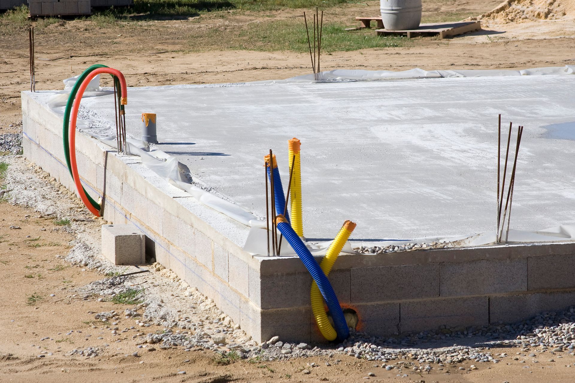 Fondations en béton avec conduits électriques et plomberie, extérieur.
