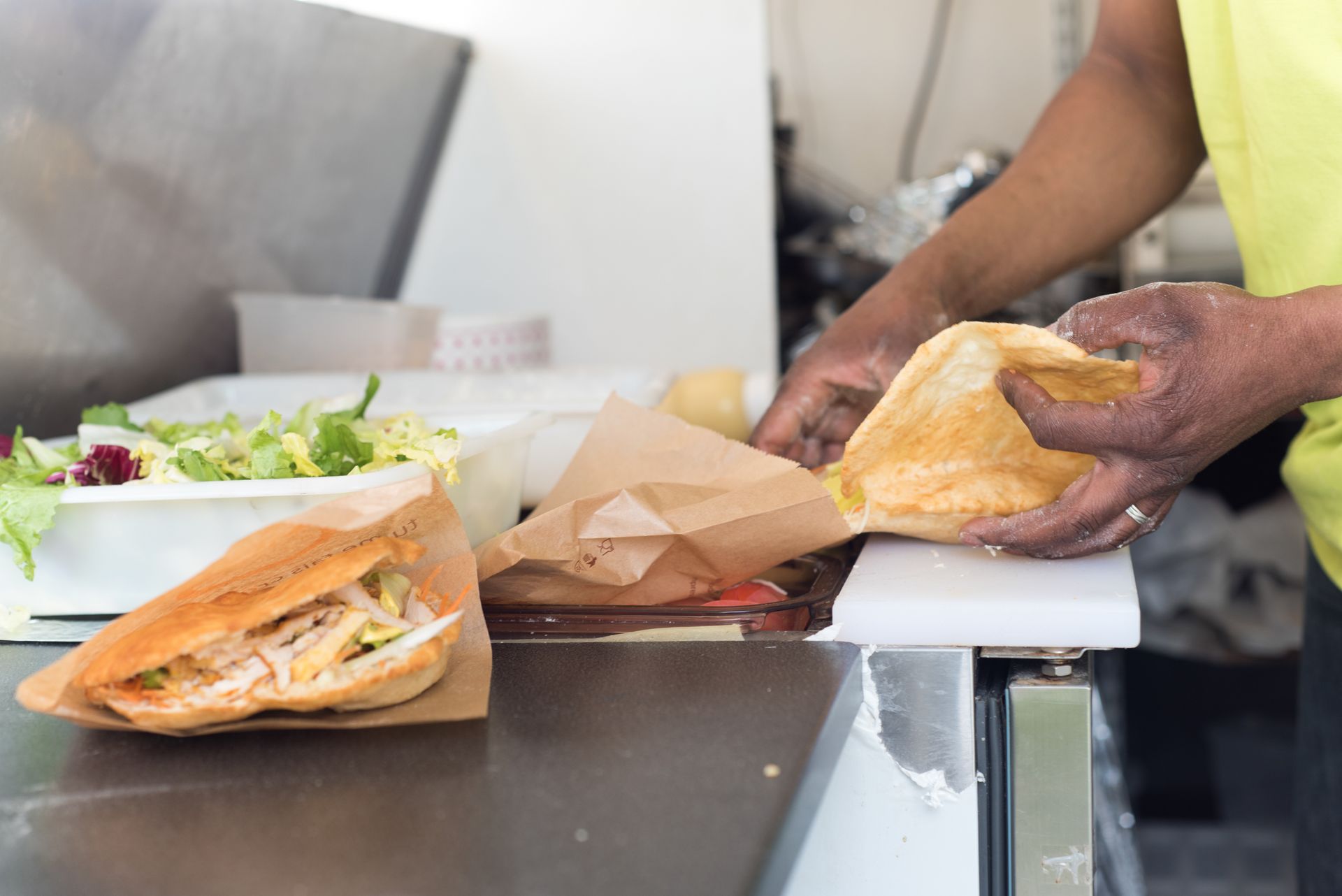 Un vendeur ambulant prépare des sandwichs sur un comptoir.