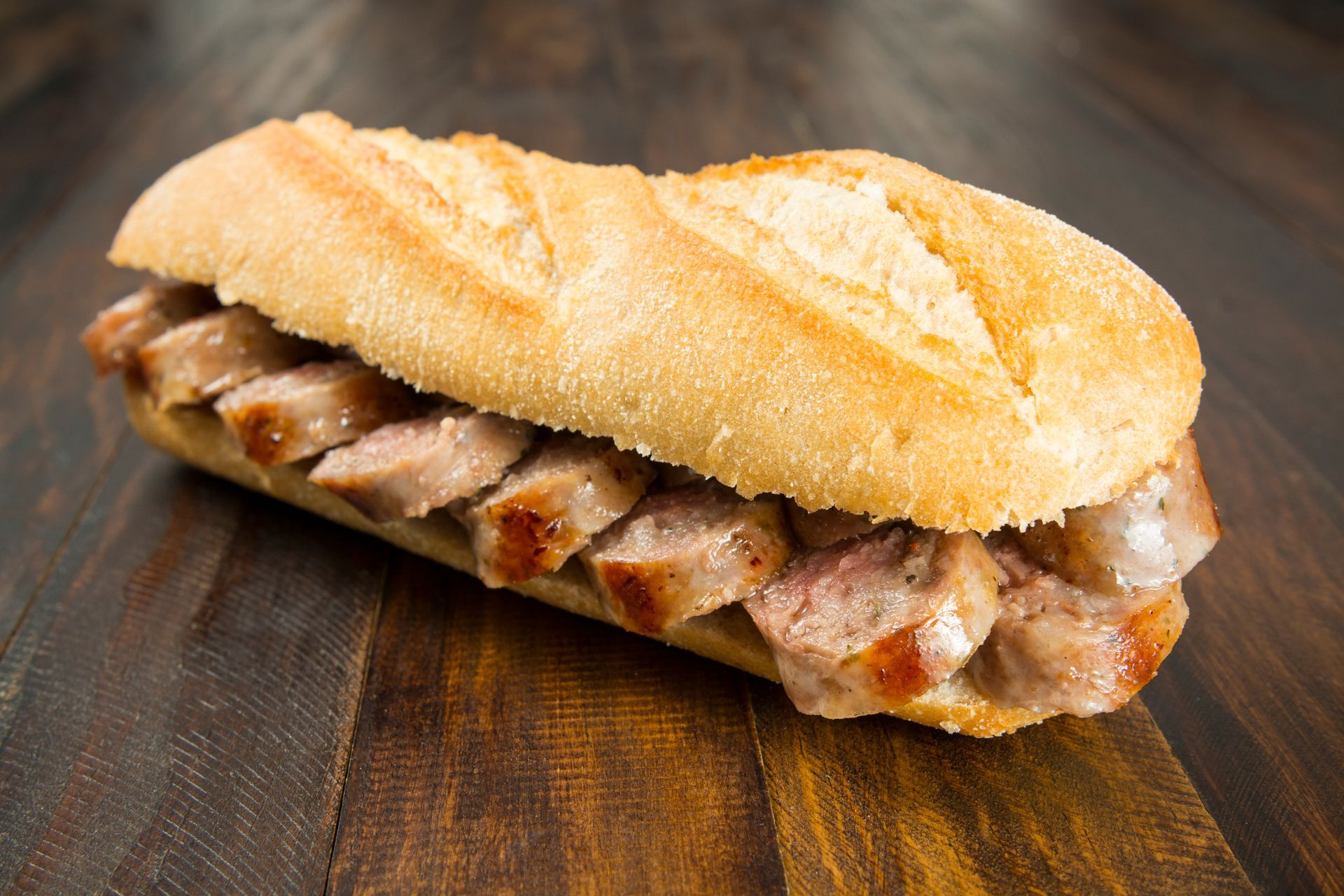 Sandwich baguette croustillante avec de la viande tranchée sur une table en bois.