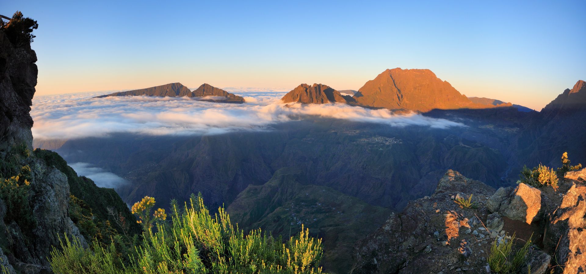Lever de soleil sur les sommets des montagnes au-dessus d'une mer de nuages.