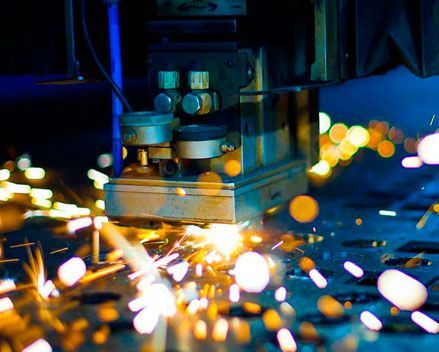 Una máquina está cortando un trozo de metal del que salen chispas.