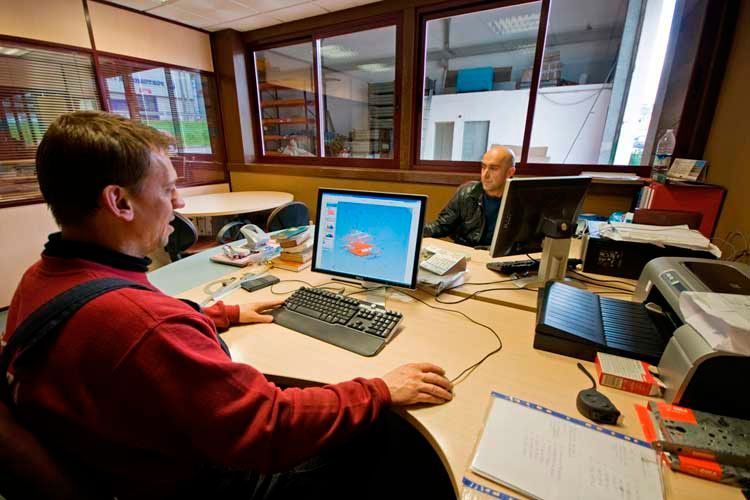 Un hombre está sentado en un escritorio frente a una computadora.