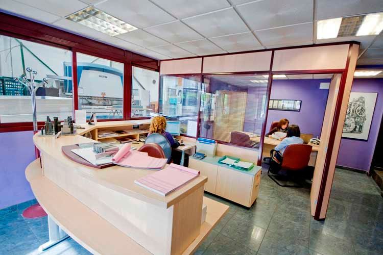 Un grupo de personas están sentadas en escritorios en una oficina.