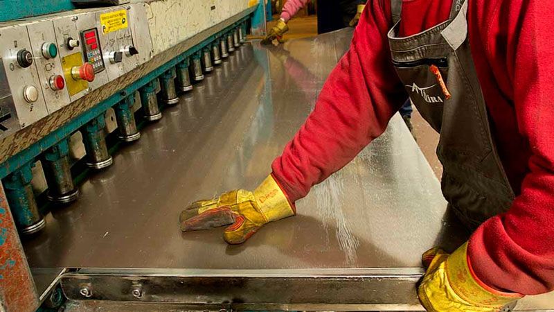 Un hombre con una camisa roja y guantes amarillos está trabajando en una máquina.