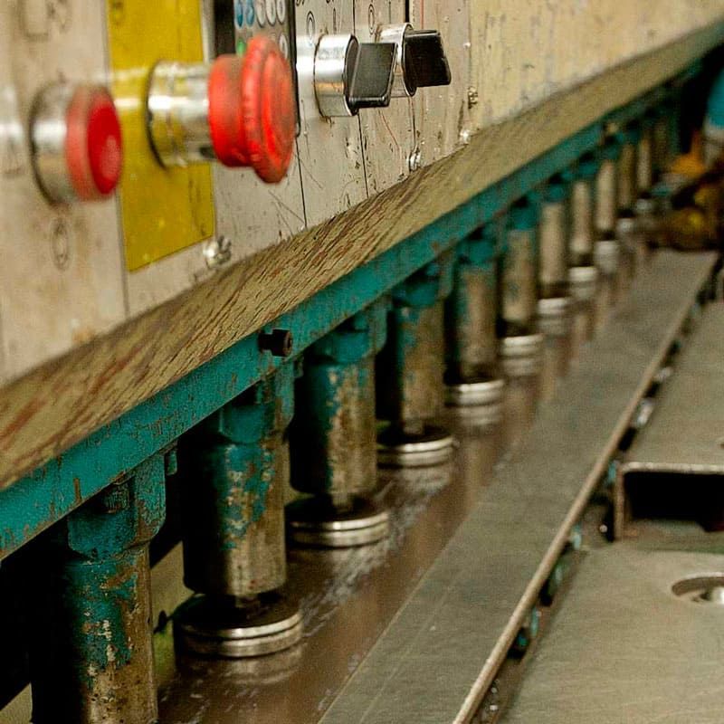 Una máquina está cortando un trozo de metal en una fábrica.