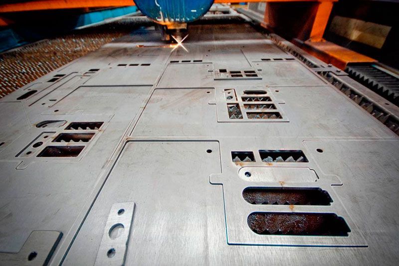 Una máquina está cortando un trozo de metal en una fábrica.