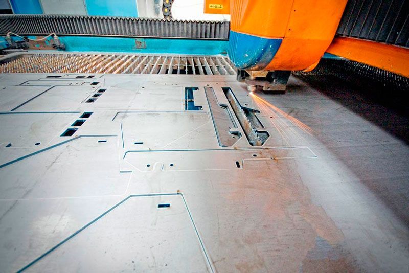 Una máquina está cortando un trozo de metal en una fábrica.