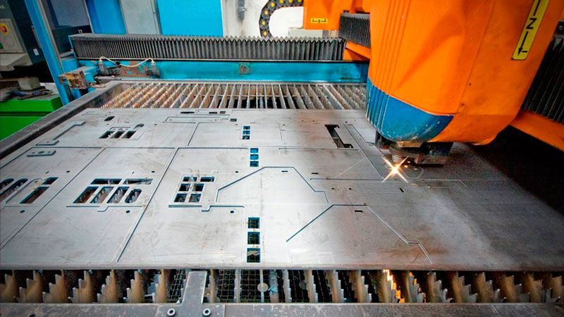 Una máquina está cortando un trozo de metal en una fábrica.