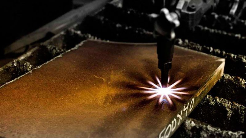 Una persona está cortando un trozo de metal con un soplete.