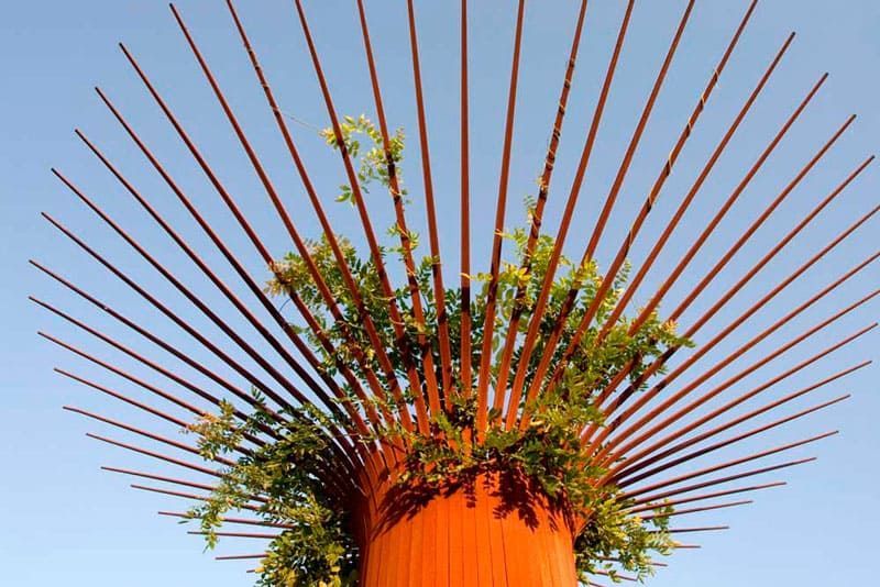 Una escultura naranja con una planta creciendo de ella.