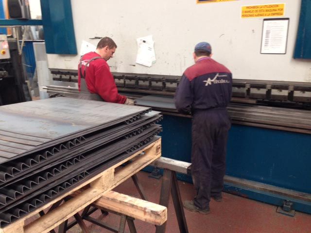 Dos hombres están trabajando en una máquina en una fábrica.