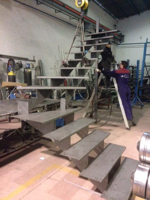 Un hombre está trabajando en un tramo de escaleras en una fábrica.