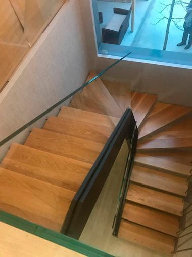 Las escaleras son de madera y tienen barandilla de cristal.