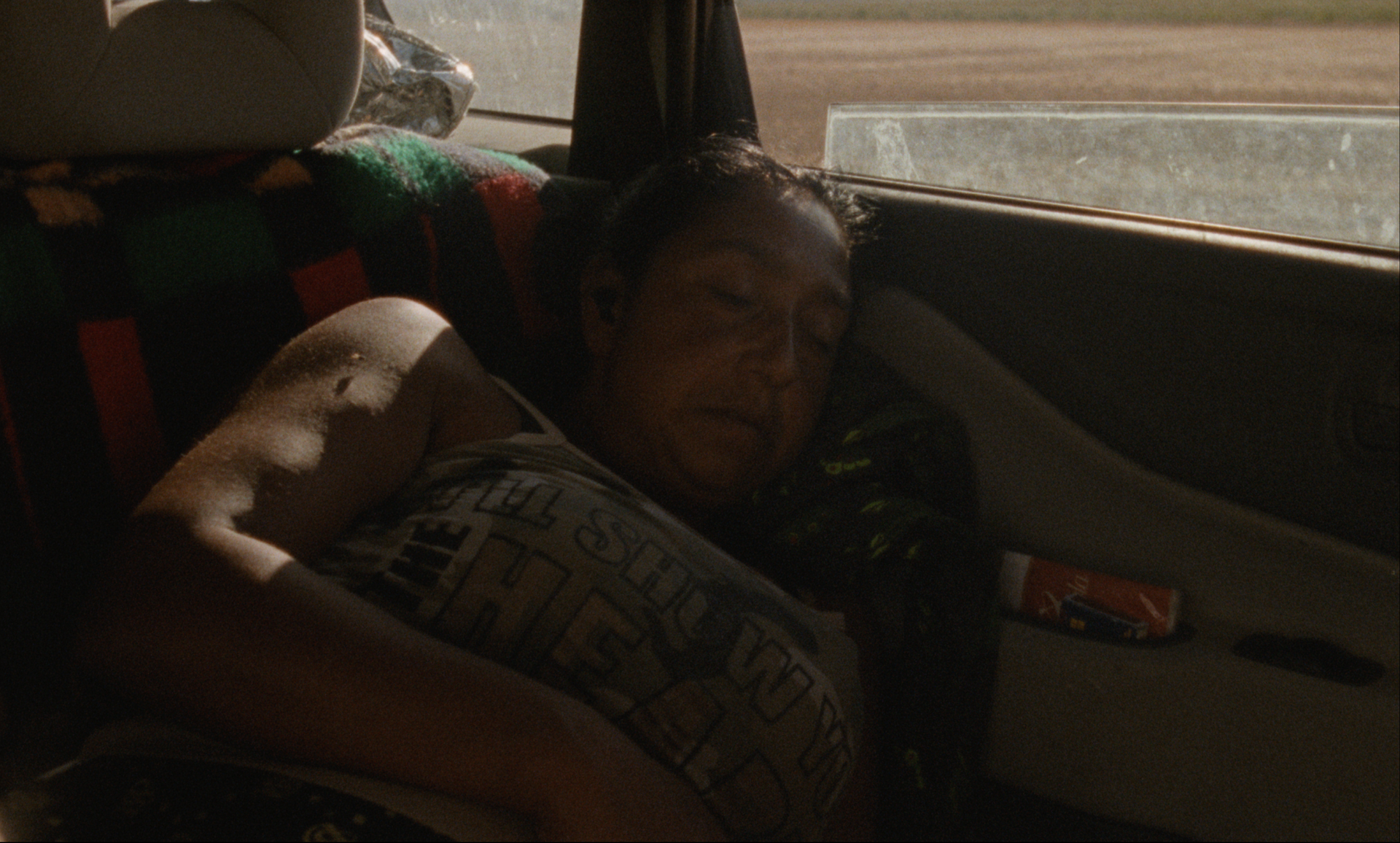 Hombre dormido en el asiento del copiloto de un coche, con la cabeza apoyada en el respaldo