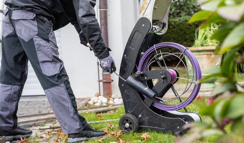 Ein Mann benutzt in einem Garten eine Abflusskamera.
