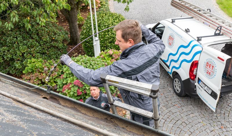 Ein Mann steht auf einer Leiter neben einem weißen Lieferwagen.