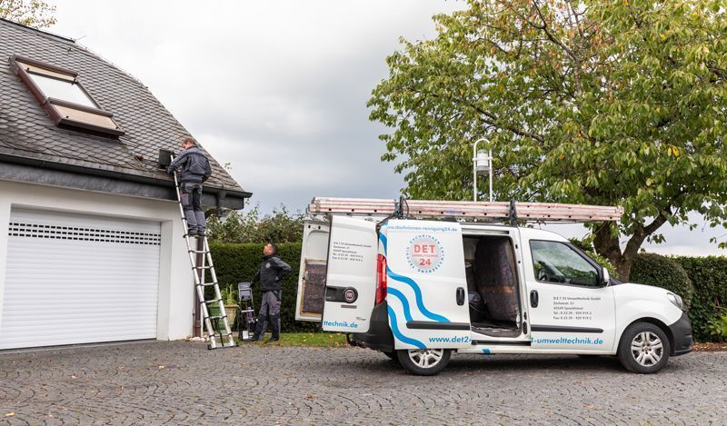 Vor einem Haus parkt ein weißer Lieferwagen mit offener Tür.