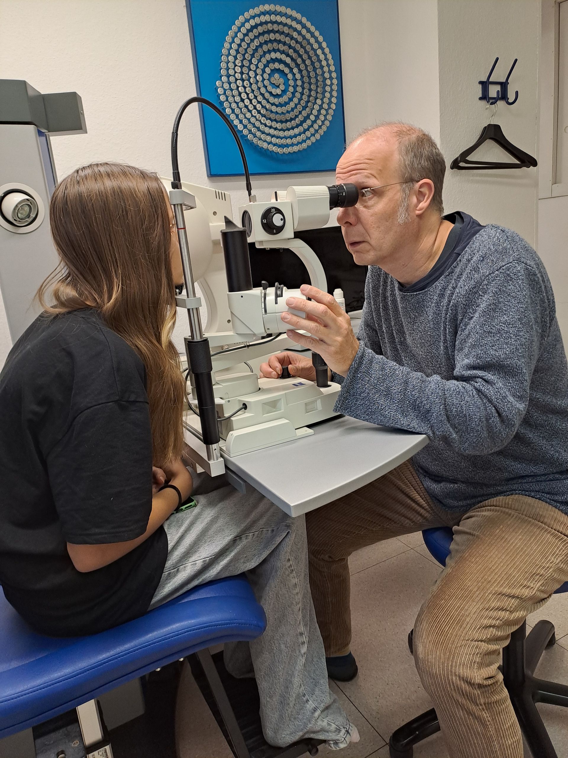 Ein Mann untersucht das Auge einer Frau mit einem Mikroskop.