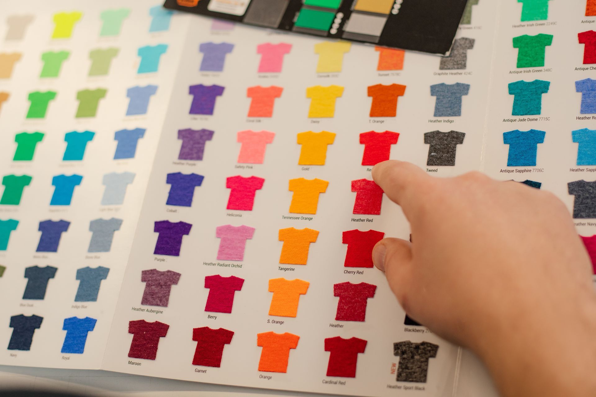 Doigt pointant un t-shirt de couleur dans un catalogue