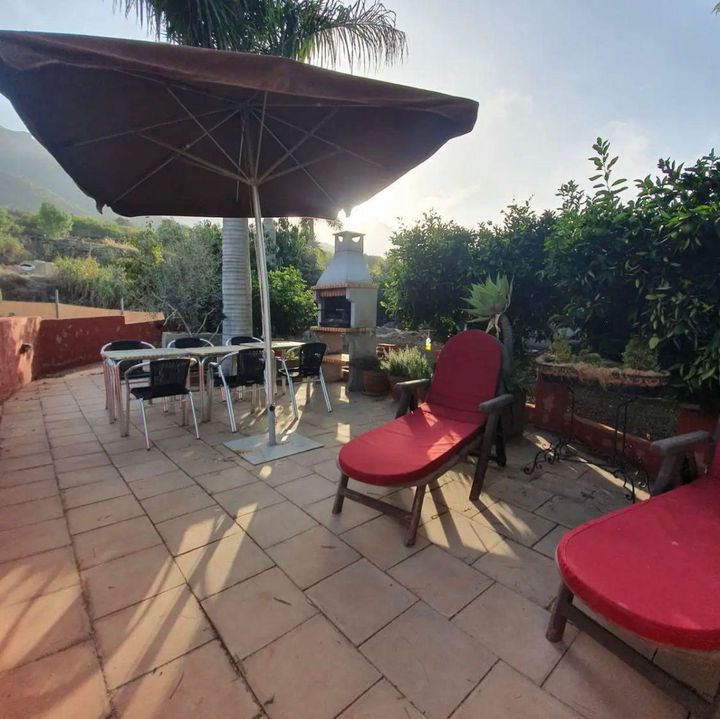 Un patio con una gran sombrilla y sillas.