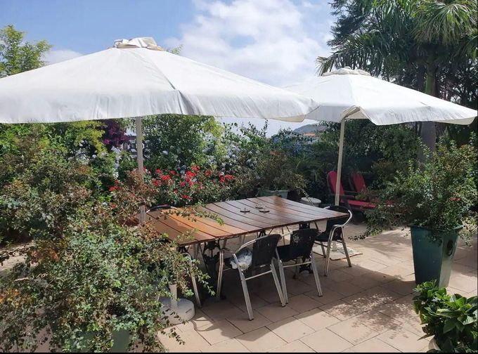Un patio con mesa y sillas bajo sombrillas blancas.