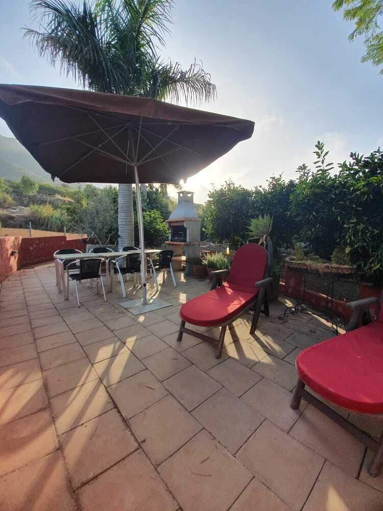 Un patio con una mesa y sillas bajo una sombrilla.