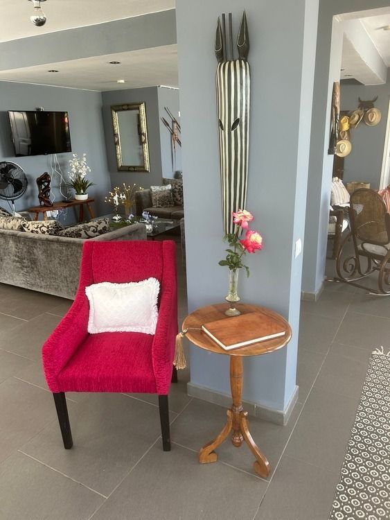 Una sala de estar con una silla roja y una mesa de madera.