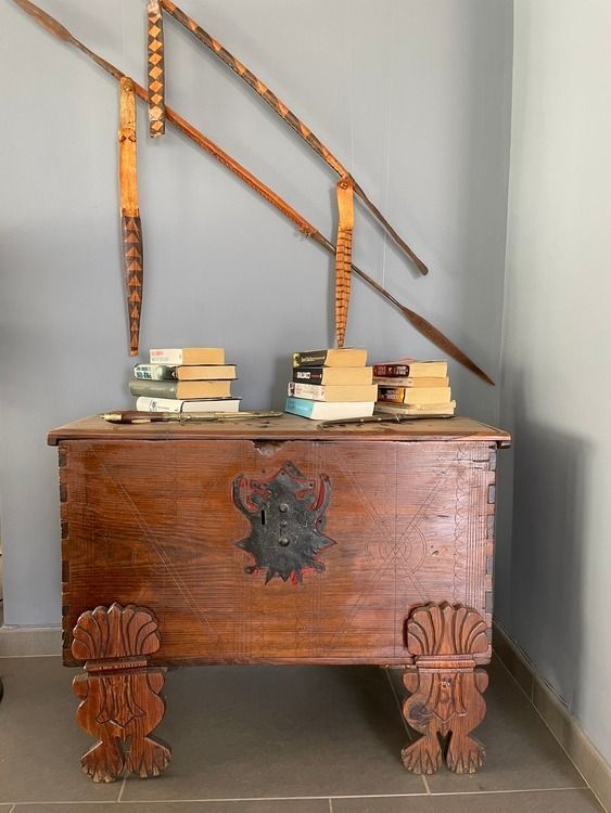 Un baúl de madera con un león encima se encuentra junto a una pila de libros.