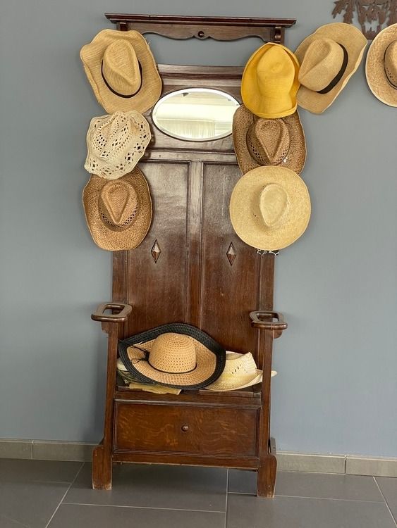 Un montón de sombreros están colgados en un perchero de madera.